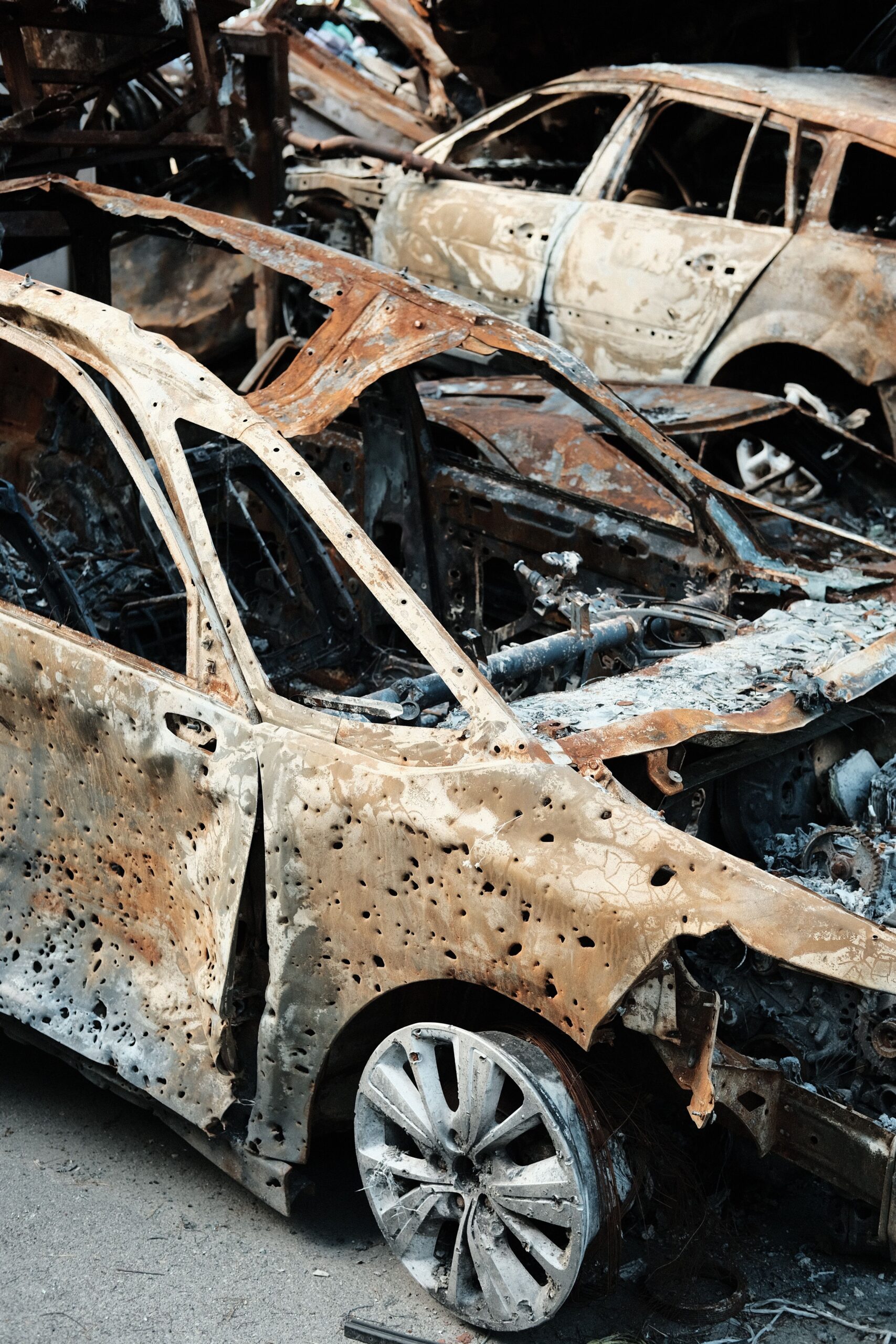 Close-up of burnt and rusty cars abandoned in a scrapyard.